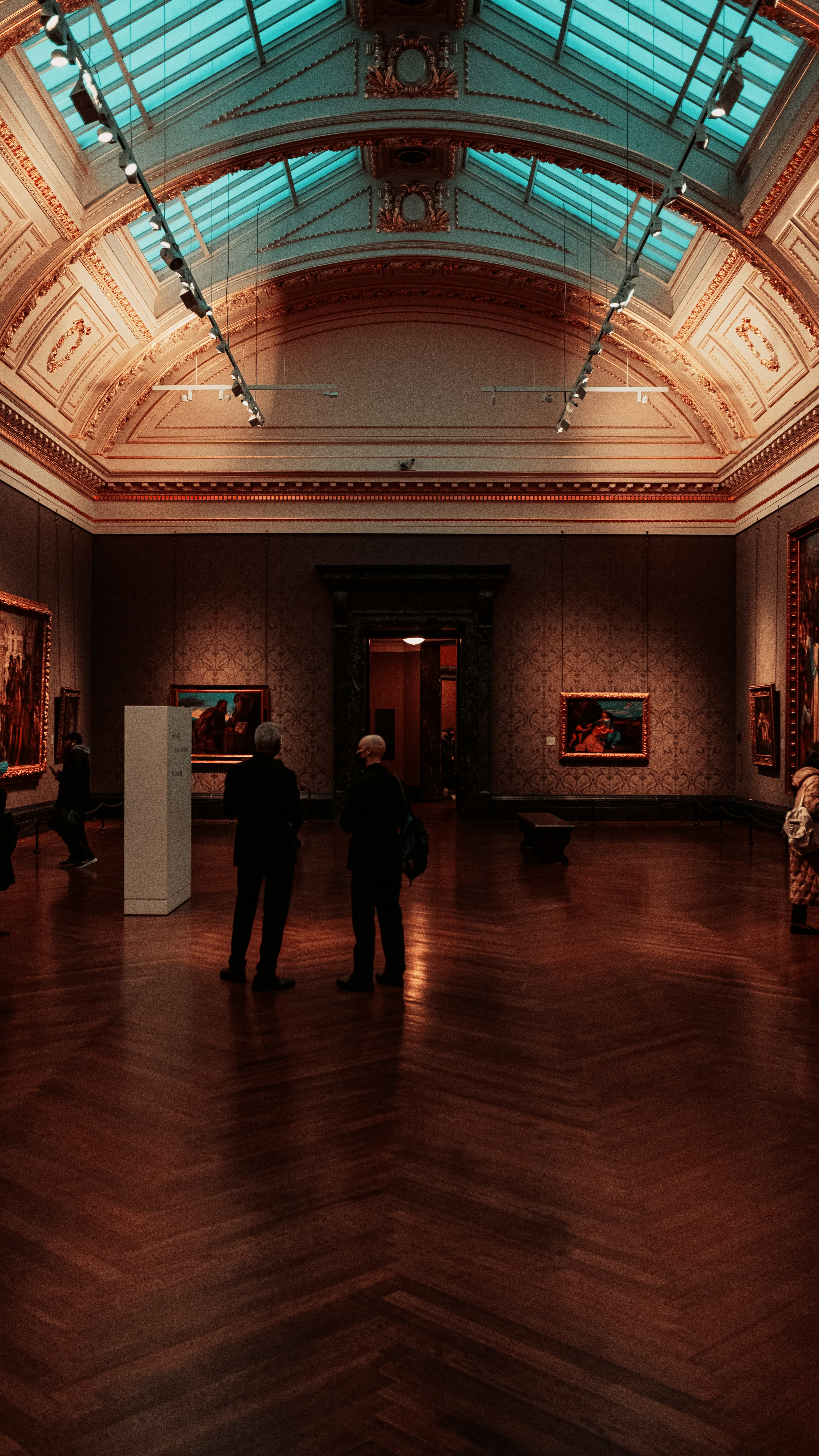 A grand museum gallery interior with ornate ceiling and blue skylights